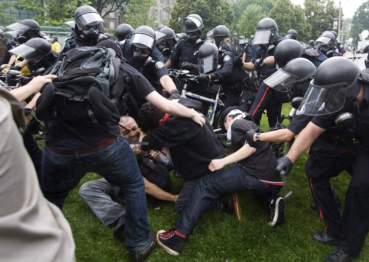 Police surround and club protesters.