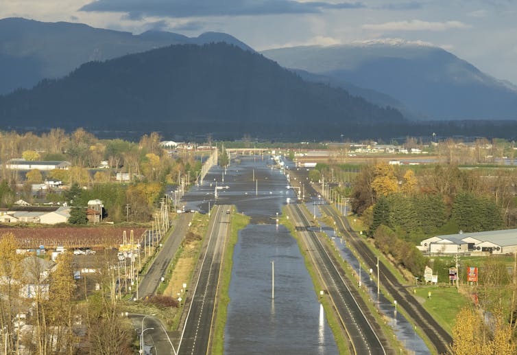 A flooded highway with mountains in the background.