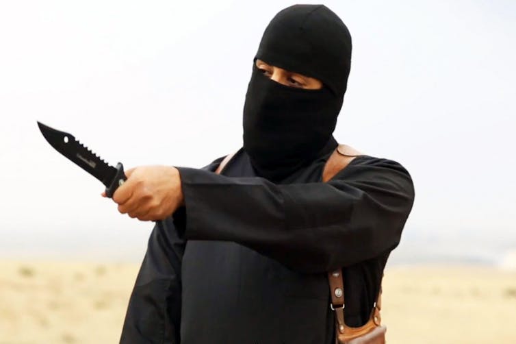 An Islamic State terrorist fighter dressed in black with a balaclava brandishing a knife.