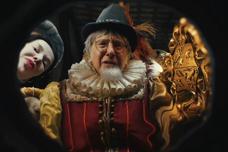 A man with white hair, glasses and a white beard wearing faux Elizabethan clothes