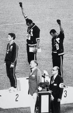 Olympic champions stand on the podium in an old photo.