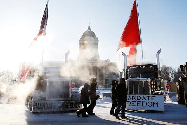 Trucks sit in front of the Manitoba Legislature with 'Mandate Freedom' written on the front of them
