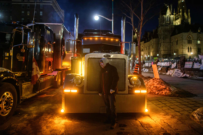 Man presses head against the grill of a semitruck.