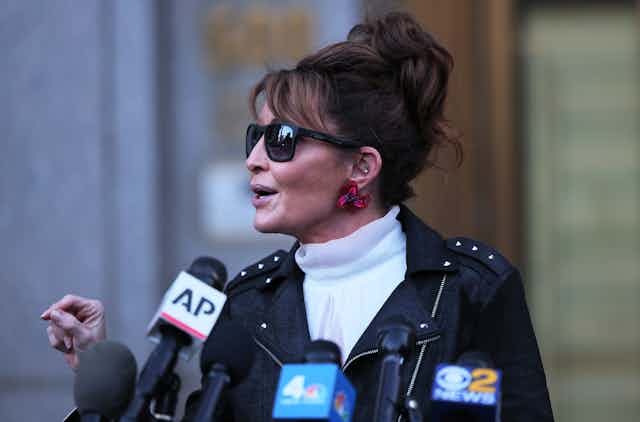 Former Alaska Governor Sarah Palin in a studded leather jacket speaks into an AP microphone
