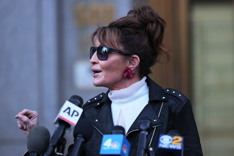 Former Alaska Governor Sarah Palin in a studded leather jacket speaks into an AP microphone