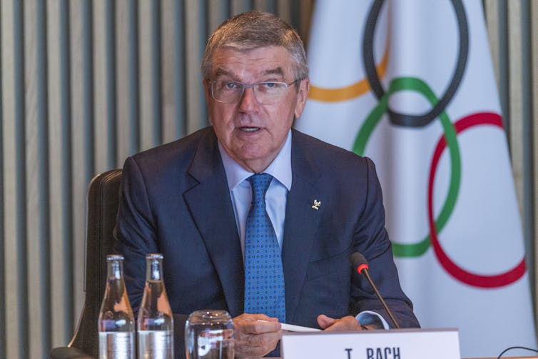 Man seated next to the Olympic flag