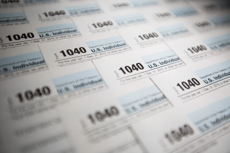 A bunch of 1040 forms a staggered on top of one another with only the top left corners of each sheet shown