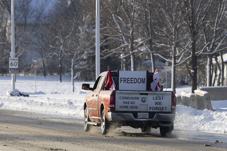 A truck is covered in signs saying 'freedom' 'communism has no home here' and 'lest we forget'