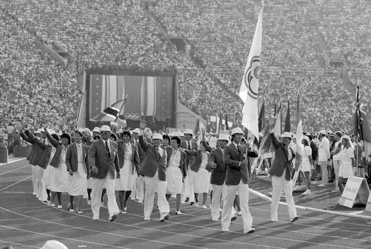 A group of people wearing matching uniforms waving at a crowd.