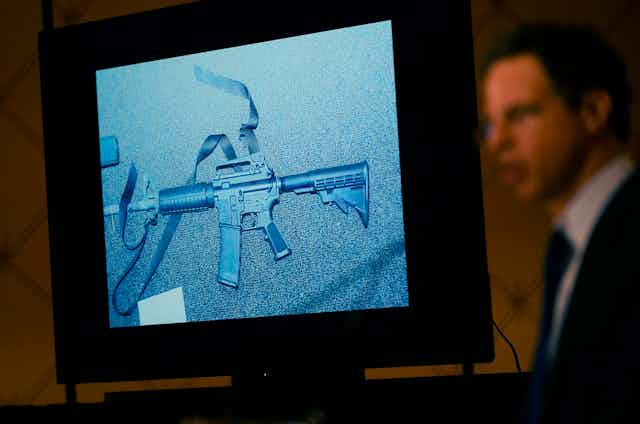 An image of the weapon used during the Newtown shooting is displayed while an attorney speaks during a news conference.