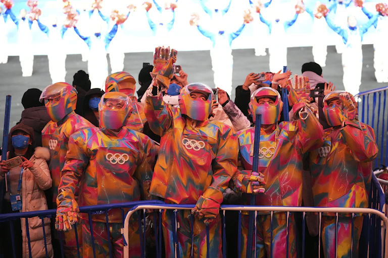 A group of people in colourful snow suits and helmets waving.