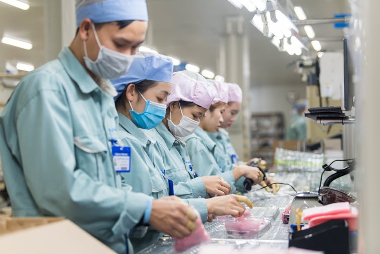A line of people work to manufacture electronic devices