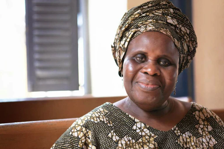 A smiling elderly woman wearing African print