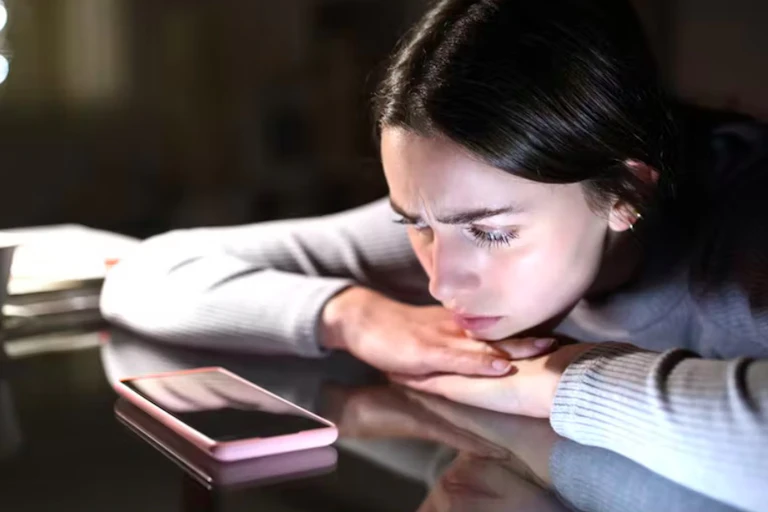Woman looking anxiously at a cellphone.