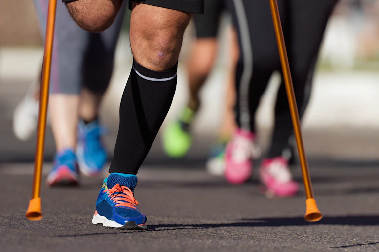 Primer plano de la parte inferior del cuerpo de un corredor de maratón, con la pierna derecha amputada (y apoyada en muletas)