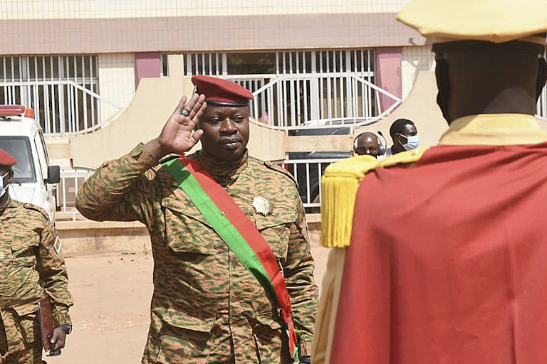 Man in military uniform salutes another man.