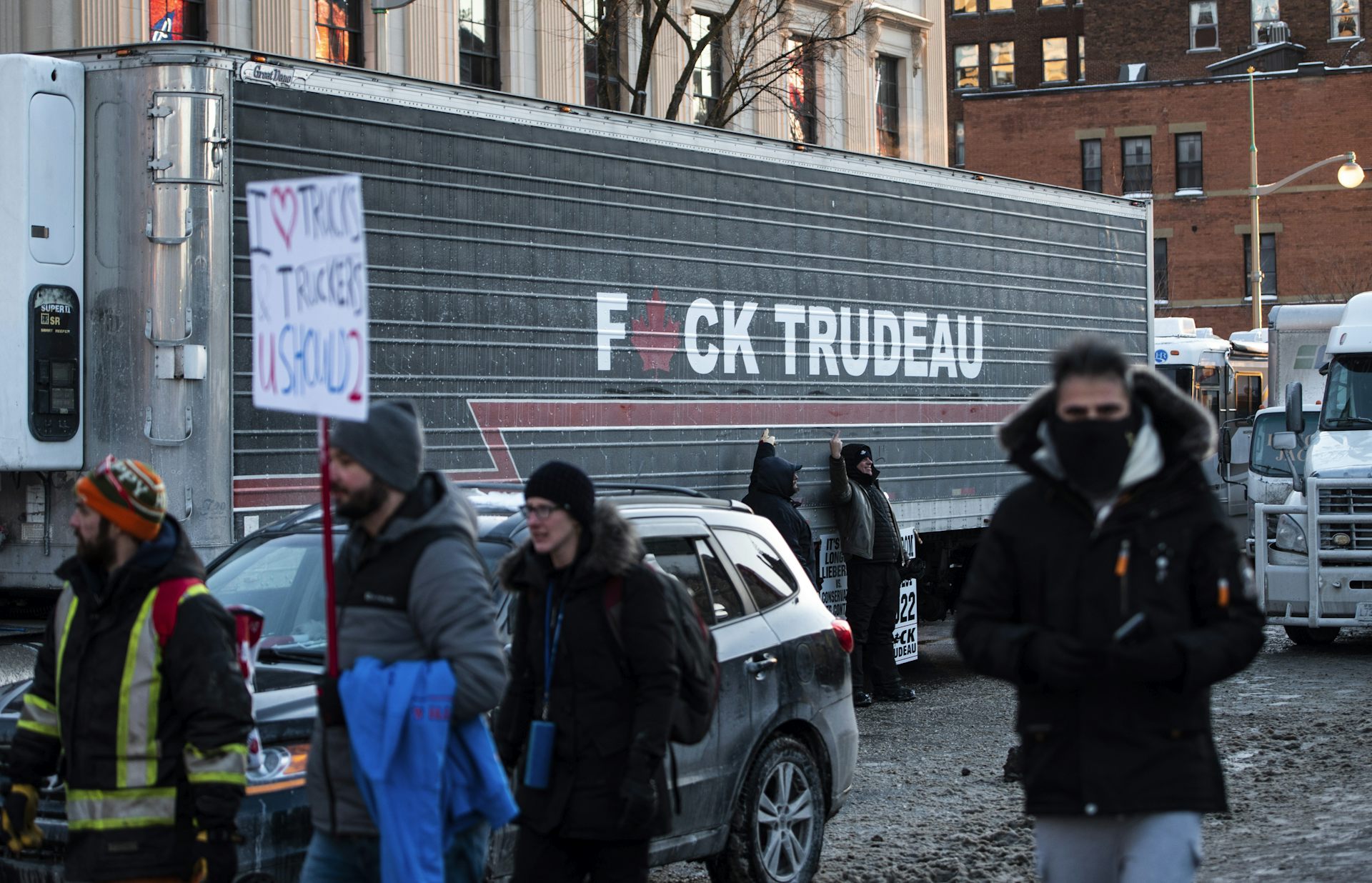 People pose beside a semi-truck adorned with the words F*CK TRUDEAU