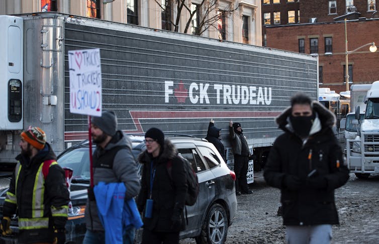 People pose beside a semi-truck adorned with the words F*CK TRUDEAU