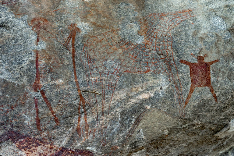 Rock wall showing ancient painting of people, giraffe