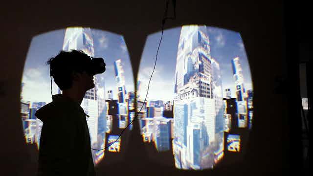 Personne avec un casque de réalité virtuelle tournée vers une projection photo d'un centre-ville sur le mur.