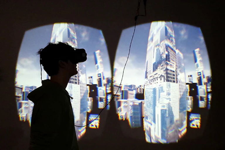 Personne avec un casque de réalité virtuelle tournée vers une projection photo d'un centre-ville sur le mur.
