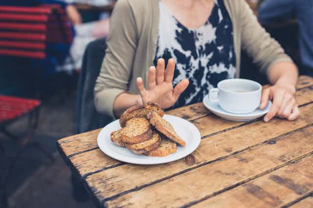 Woman a cafe pushes a plate of bread away.