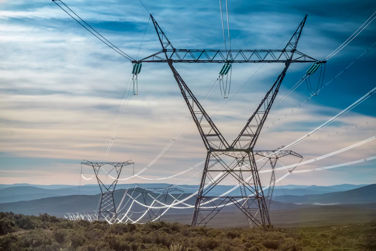 Electricity transmission towers with the early morning light gleaming off the cables.