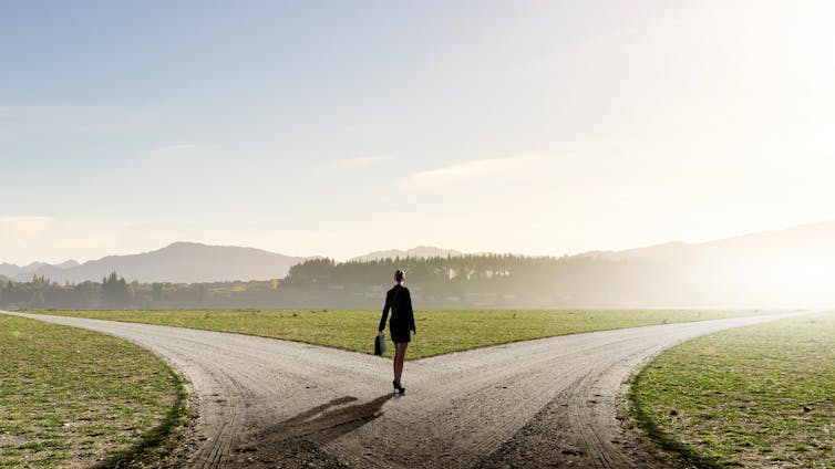 Businesswoman standing at fork in a road.