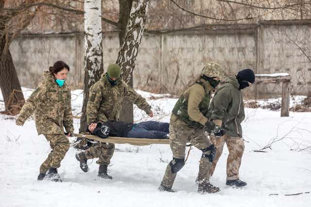 Four people carrying a stretcher.