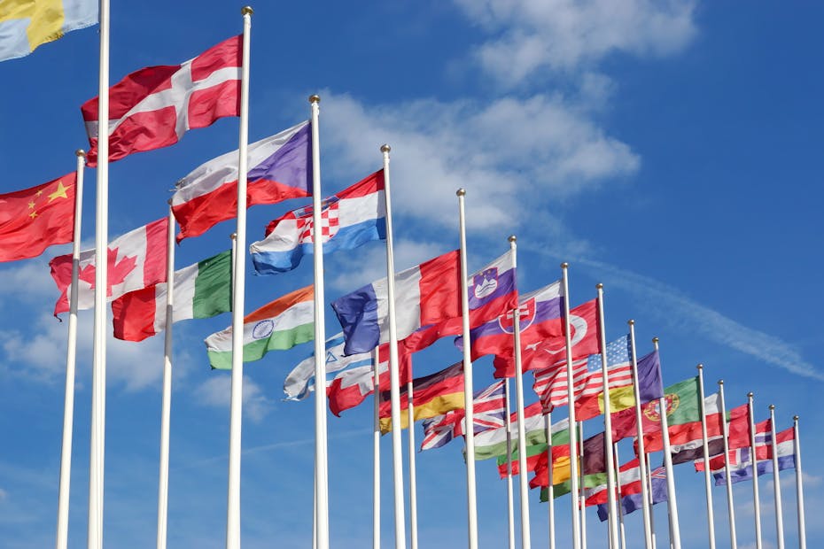 22 flags representing mostly western countries fly in front of a blue sky.