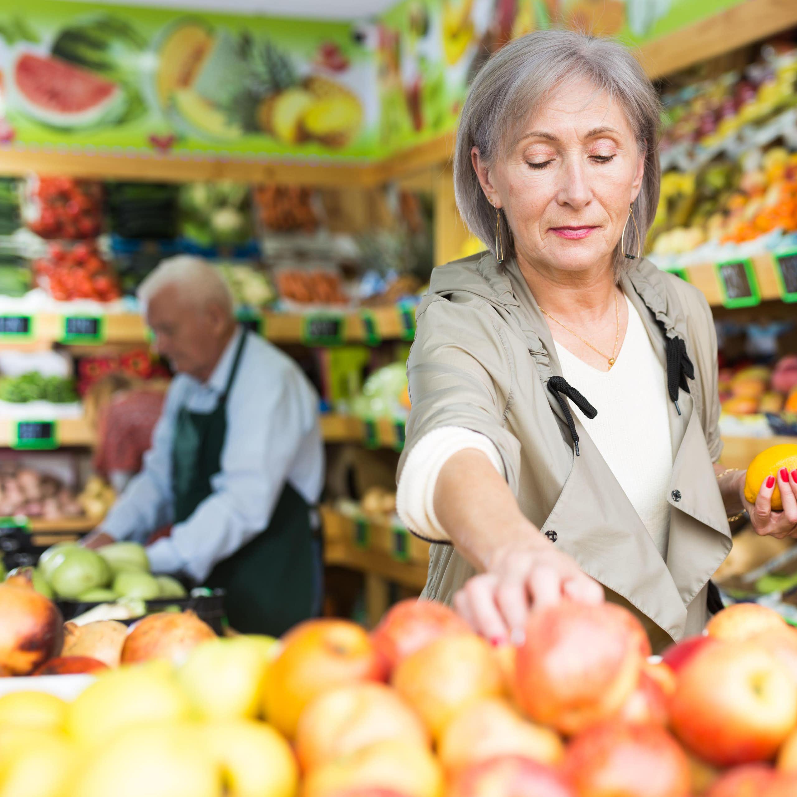 Une femme manipule des fruits dans un marché d'alimentation