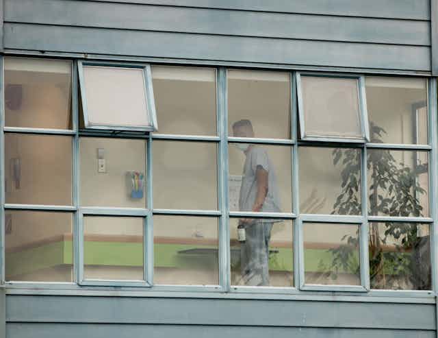 A person in scrubs seen through windows