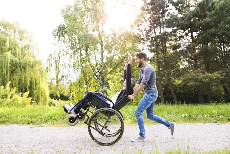 A man excitedly pushes an elderly person in a wheelchair