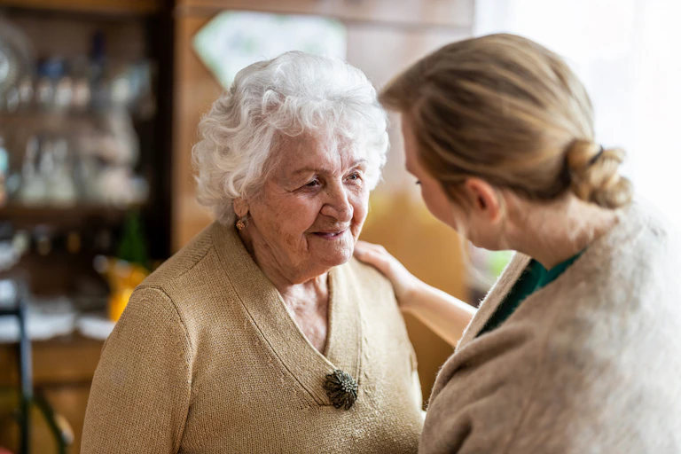 younger woman helps older woman kindly