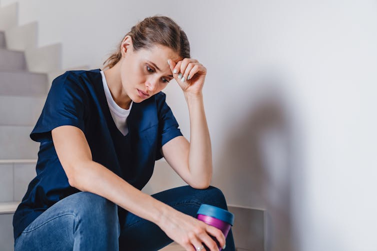 Tired female worker sits on stairs