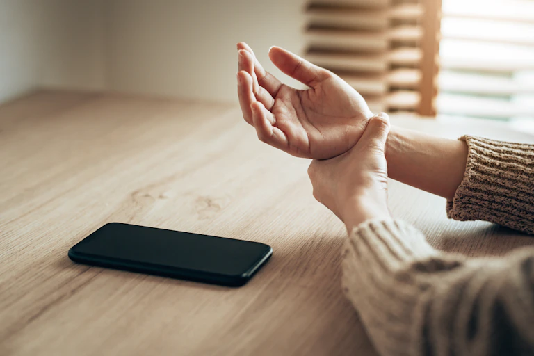 person rubs wrist with phone nearby