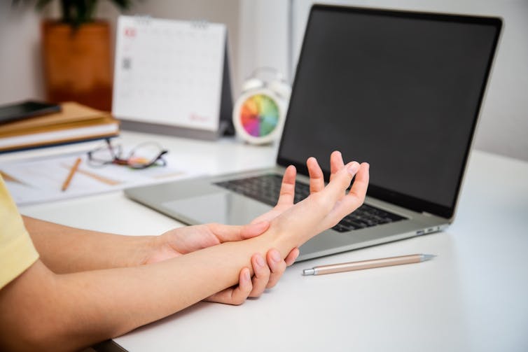 person sits at desk with sore wrist