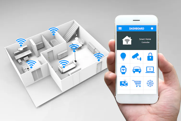 Someone holds up a smart phone next to a model of a home.