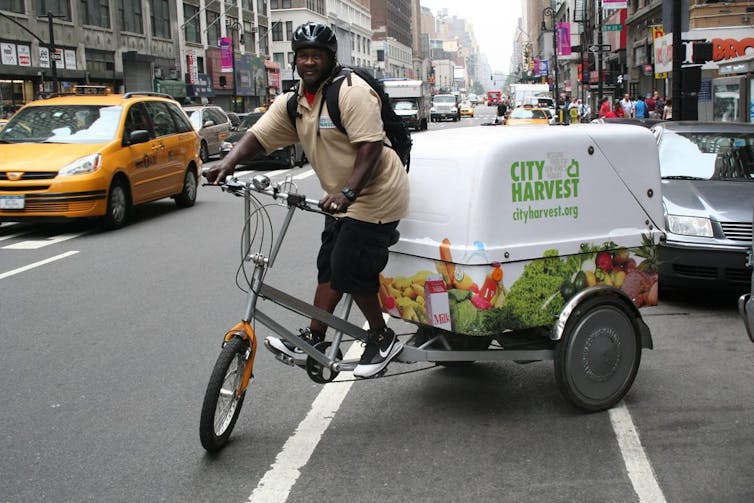 A person rides a cargo bike on a city road