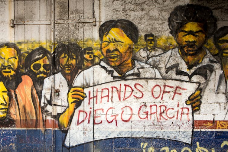 A painted mural features people protesting with banners.