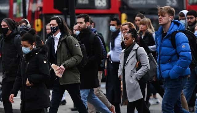 People in face masks crossing a road in London