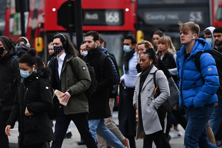 People in face masks crossing a road in London
