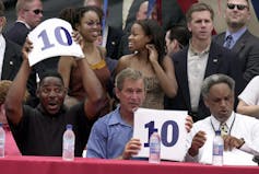 Two judges hold up score cards amid a crowd of people.