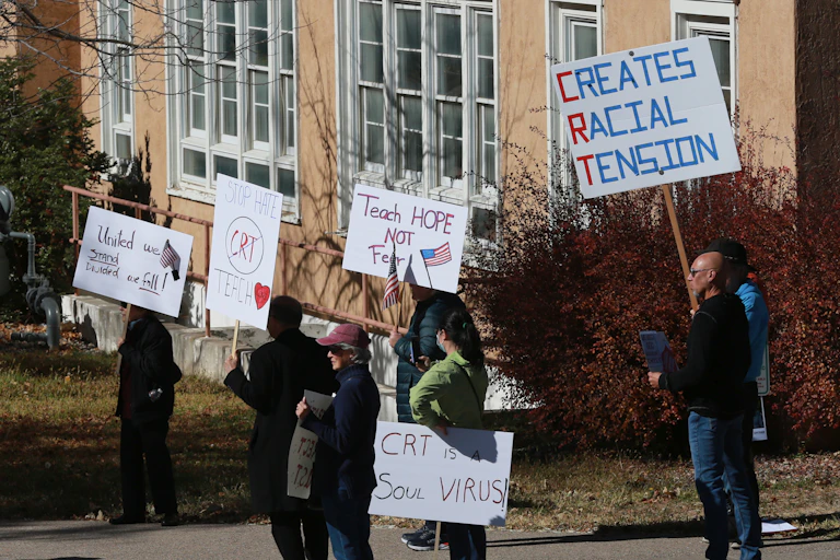 People hold signs reading 'CRT is a soul virus' 'teach hope not fear' and 'stop hate, don't teach CRT'