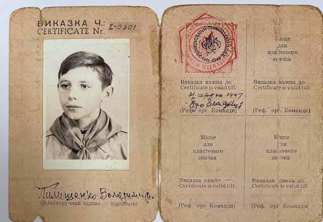 A black and white photo of a young boy is affixed to an old ID card from the 1930s.