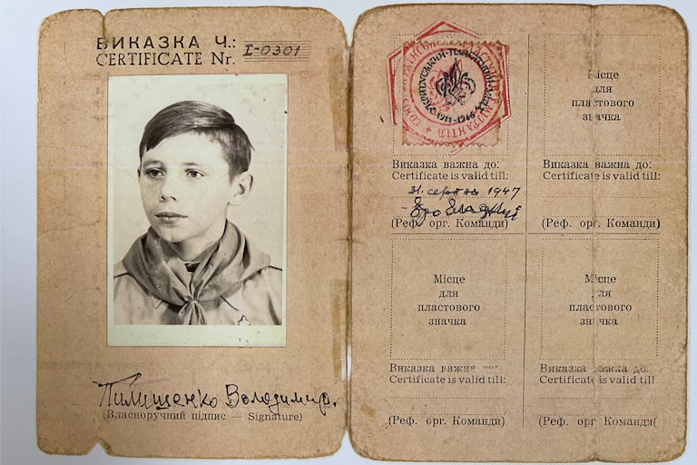 A black and white photo of a young boy is affixed to an old ID card from the 1930s.