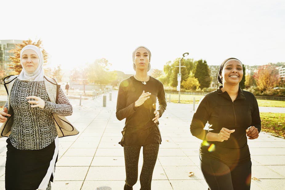 Three Muslim women wearing sports hijab and running together.