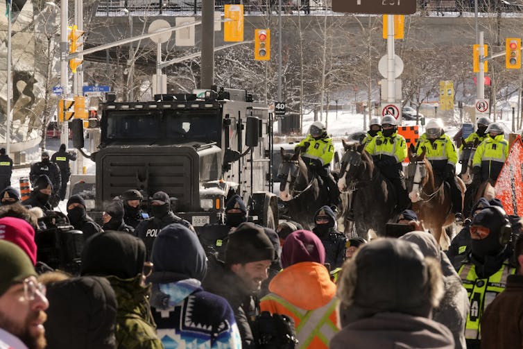 Protesters stand as police on horseback and tactical units approach
