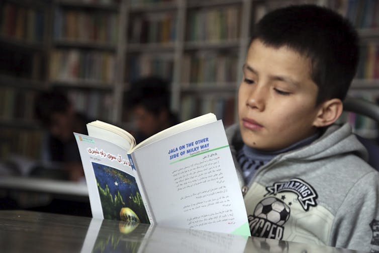 Close-up of a boy's face seen reading a book about the milky way.