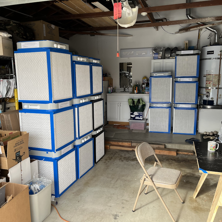 about a dozen boxes with taped edges stacked in a garage
